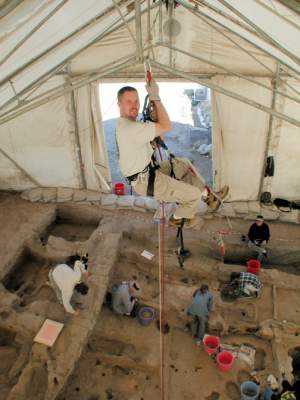 Figure 13: Michael Ashley-Lopez suspended from the tent rafters in order to take vertical photos of the BACH1 excavation